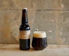 Load image into Gallery viewer, Bottle and glass of The Kernel Brown Ale against a textured wall.
