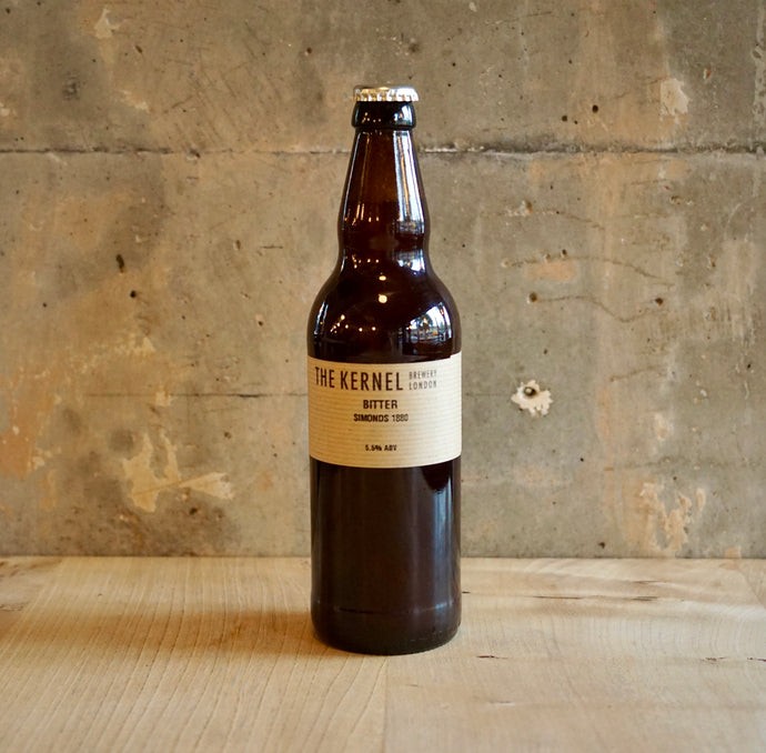 Beer bottle with a label on a wooden surface and concrete wall background