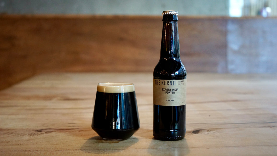 Bottle of Export India Porter from The Kernel Brewery and glass of dark beer on a wooden surface