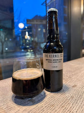 Load image into Gallery viewer, Bottle and glass of The Kernel Imperial Brown Stout on a table with a cityscape background
