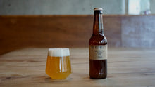 Load image into Gallery viewer, Bottle of The Kernel Brewery's India Pale Ale and glass on a wooden table with a blurred background
