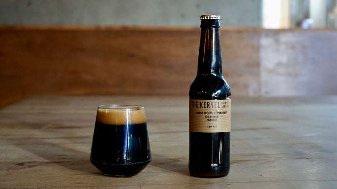 Dark beer bottle and glass on a wooden surface with a blurred background