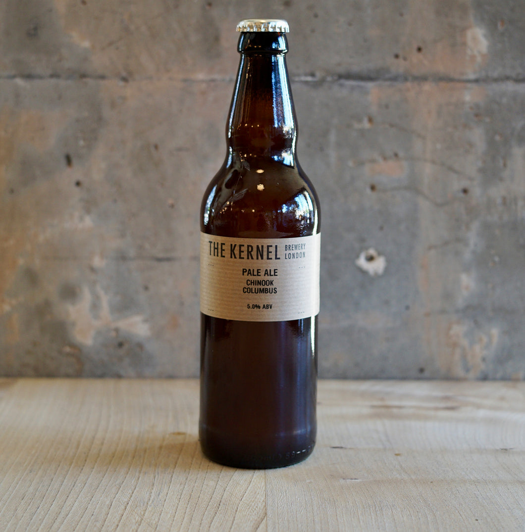 Brown beer bottle with a label on a wooden surface and concrete wall background