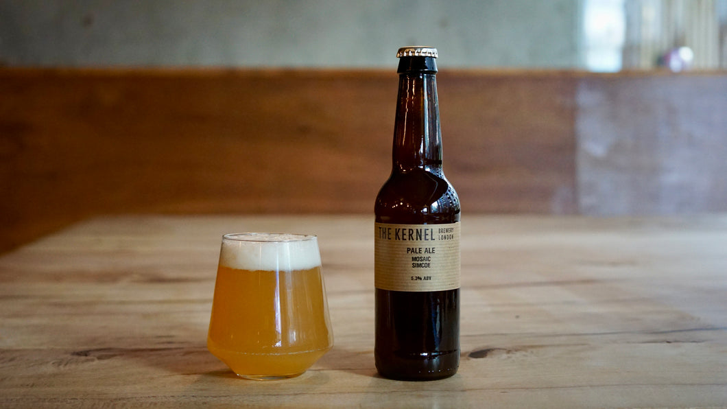 Bottle of Pale Ale from The Kernel Brewery and glass of beer on a wooden surface with a blurred background